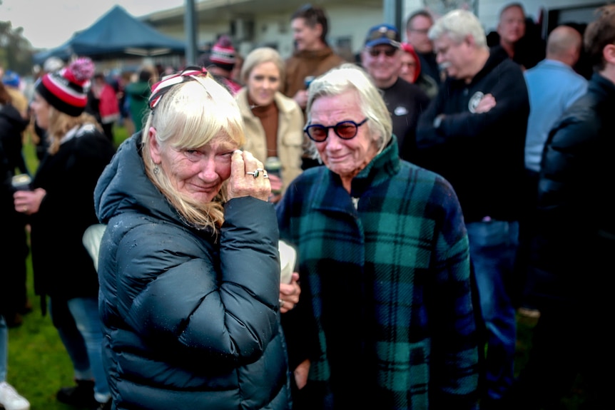 Woman in jacket appears upset amid group of other football spectators