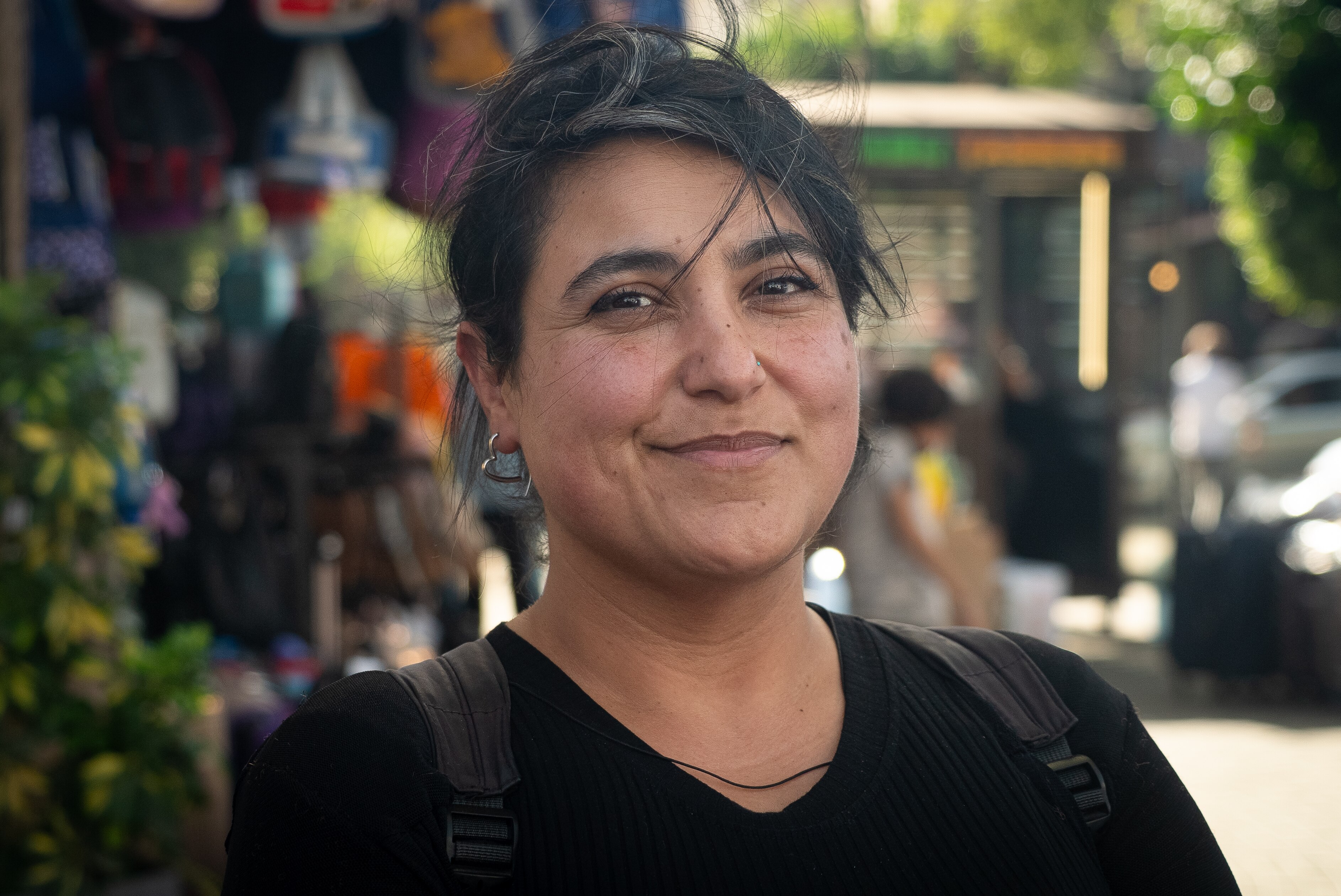 A woman with windswept black hair gives a tight smile