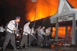 Police secure the entrance of a burning prison