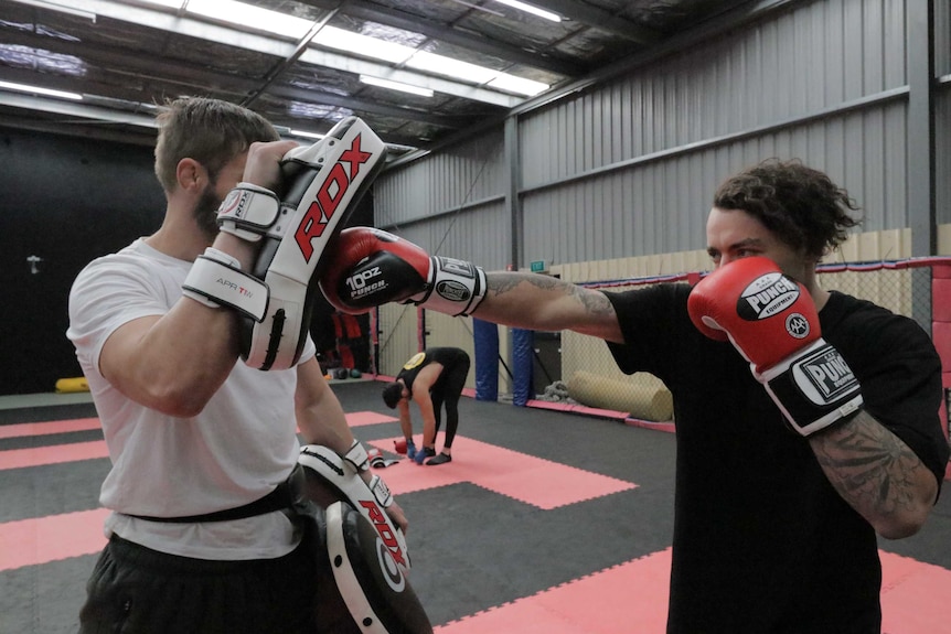 Two mixed martial arts fighters training in a gymnasium