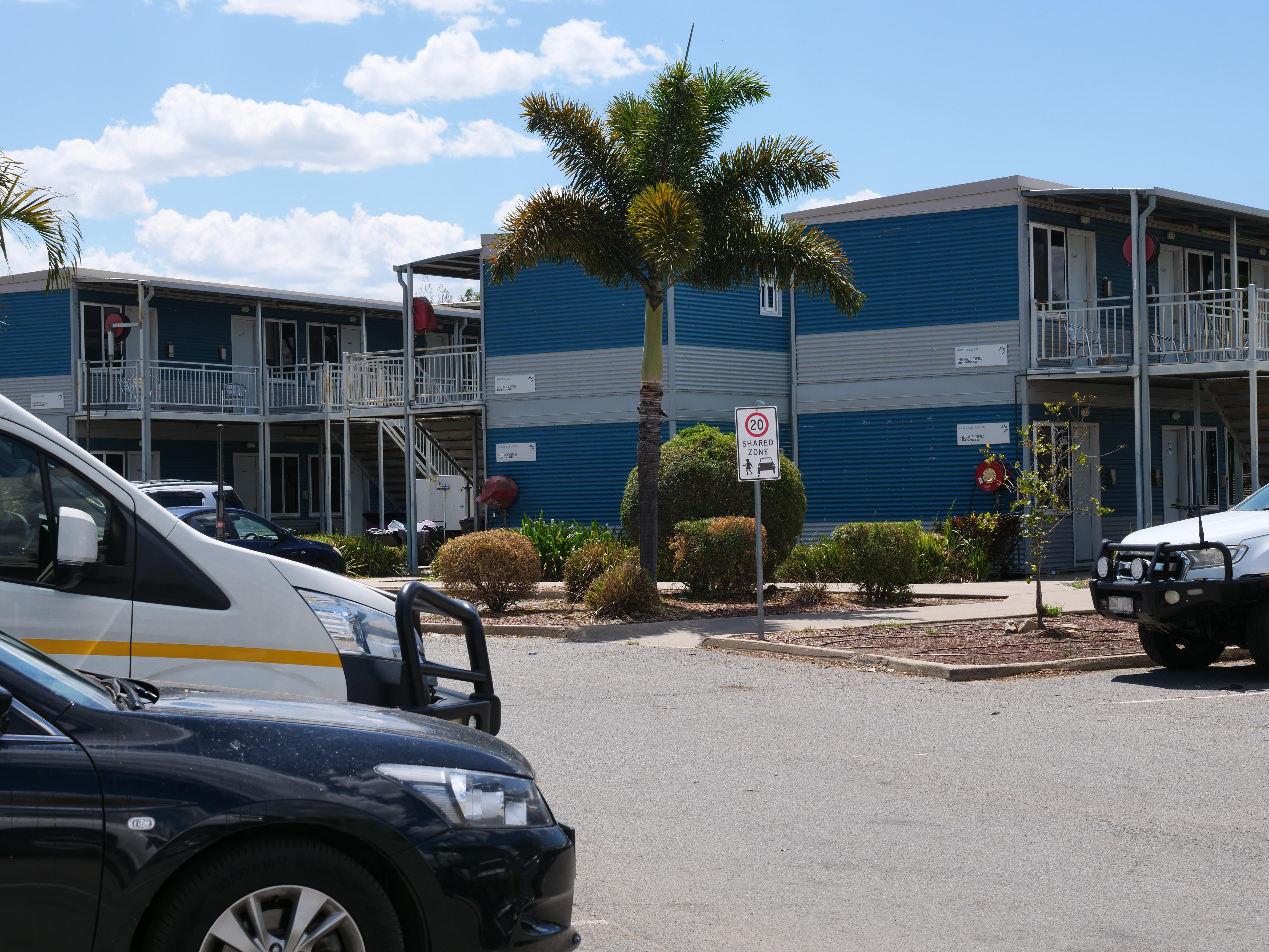 Desde el estacionamiento de un pueblo minero se pueden ver unidades de vivienda de dos pisos y balcones. 