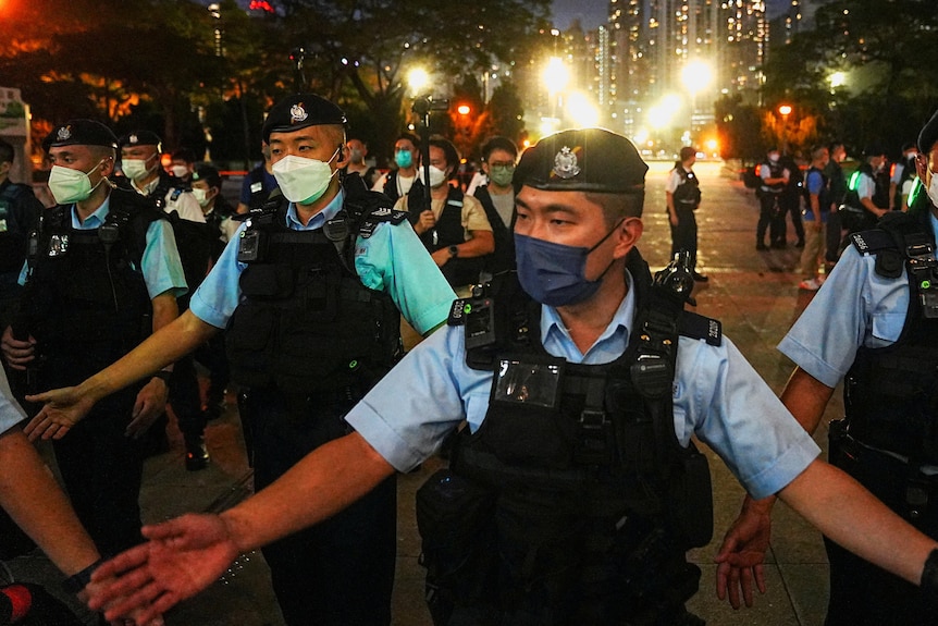 Police in face masks herd people away from a square