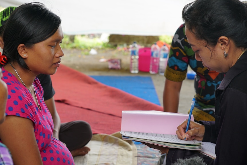 A pregnant woman is examined by midwifes in an evacuation centre.