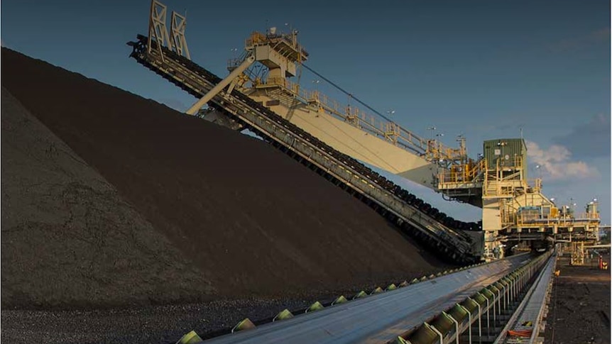 Heavy machinery sits above a large pile of coal at the Grosvenor mine at Moranbah.