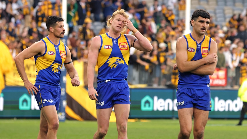 Three West Coast Eagles player, Liam Duggan, Reuben Ginbey and Thomas Cole, looking dejected as they walk off a field