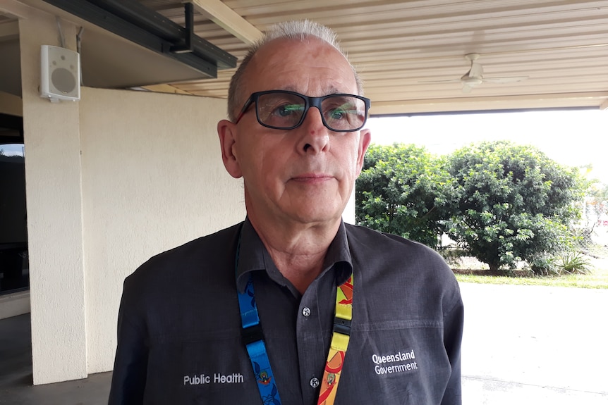 a man wearing dark glasses and a charcoal polo shirt with a colourful lanyard
