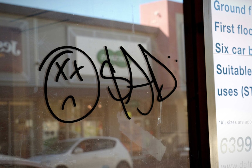 Graffiti saying 'sad' sprayed on a wall of an empty shop in Armadale