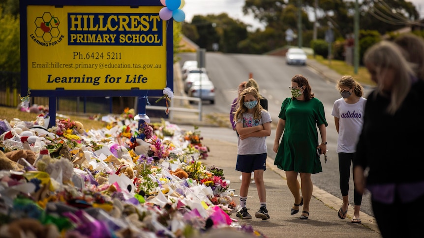 A Hillcrest Primary School sign with hundreds of bunches of flowers arranged on the ground nearby, a