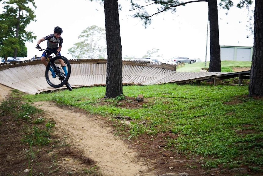 Kid launching mountain bike off jump