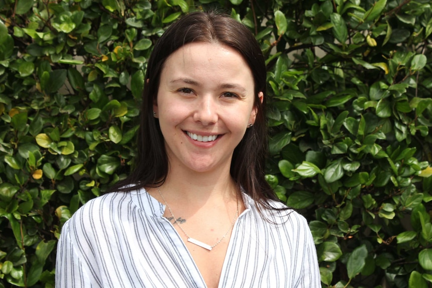 Sarah Larcombe against a backdrop of green foliage.