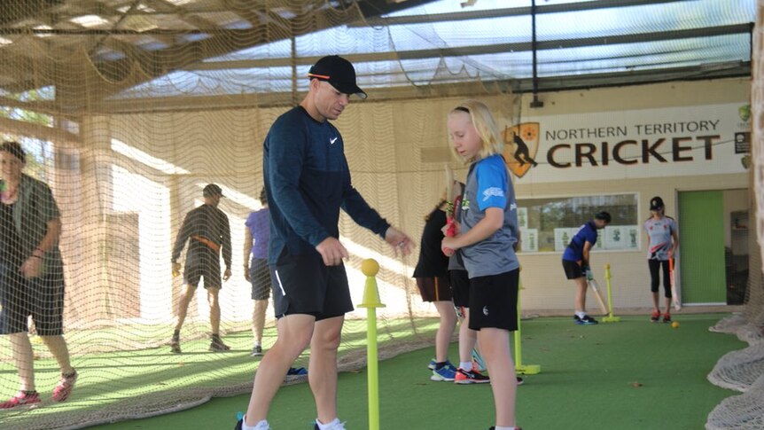 David Warner shows a girl how to play cricket in Darwin.