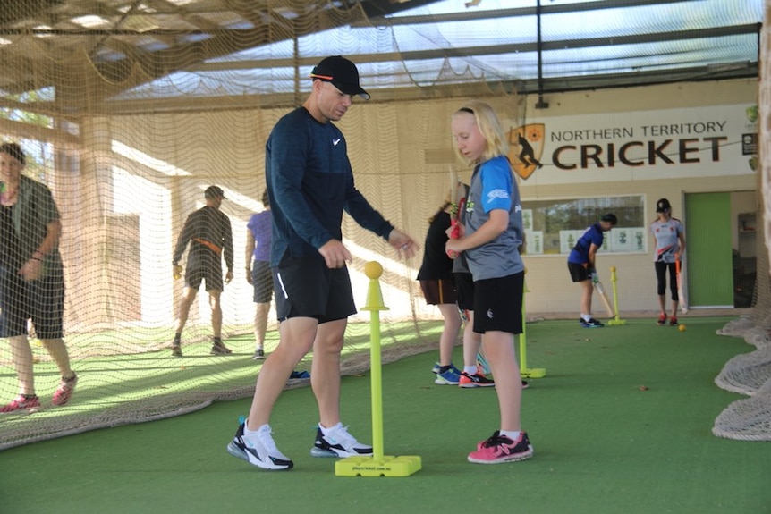 David Warner shows a girl how to play cricket in Darwin.