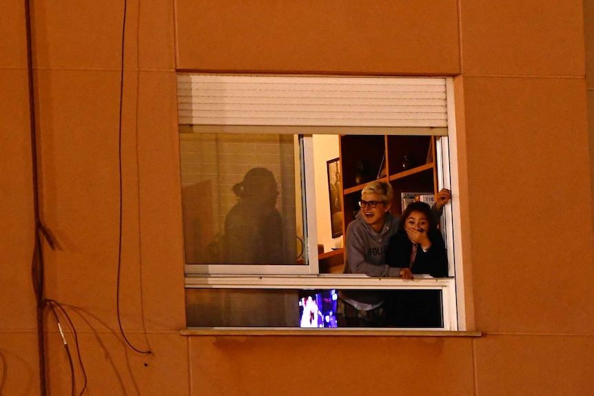 People cheer on from apartment windows.
