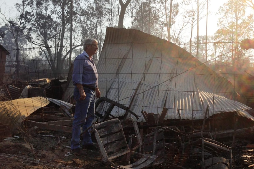 Ron Fuller stands in the ruins of his home