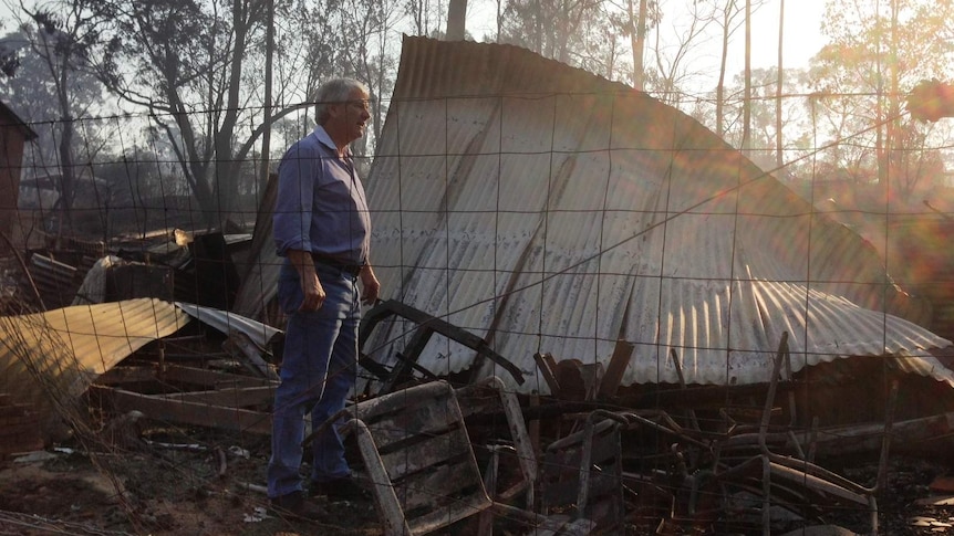 Ron Fuller stands in the ruins of his home