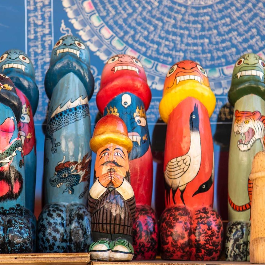 A row of painted Asian wooden penis sculptures featuring animals on them