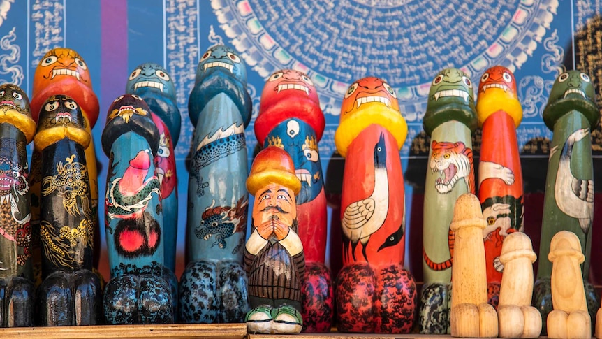 A row of painted Asian wooden penis sculptures featuring animals on them