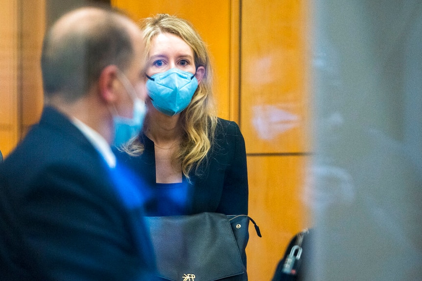 Elizabeth Holmes through a glass window.