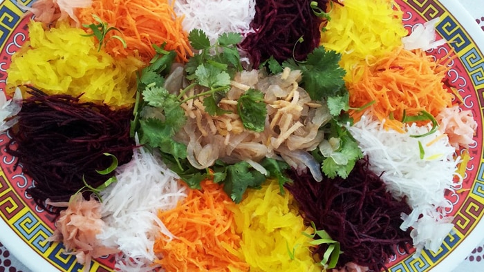A top down picture of a multicoloured salad comprised of noodles and vegetables 