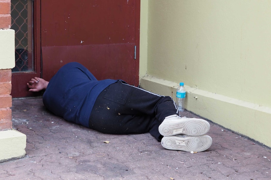 A person sleeping rough in a doorway.