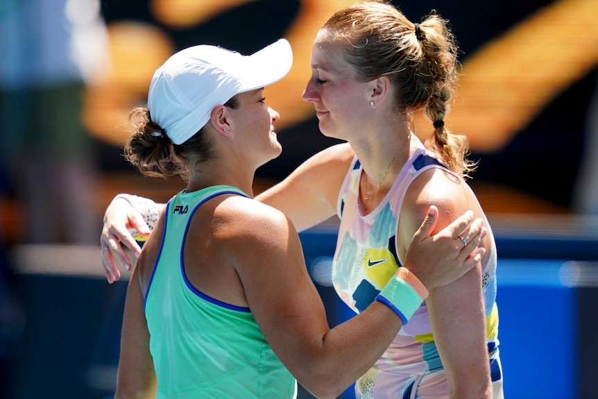 Two female tennis players embrace at the net as they congratulate each other at the Australian Open.