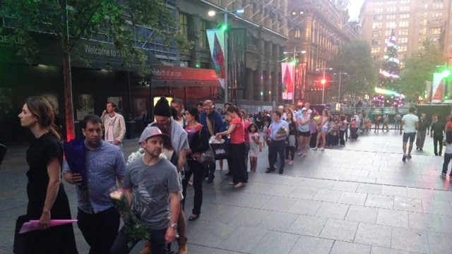 A line of people wait to leave floral tributes in Martin Place