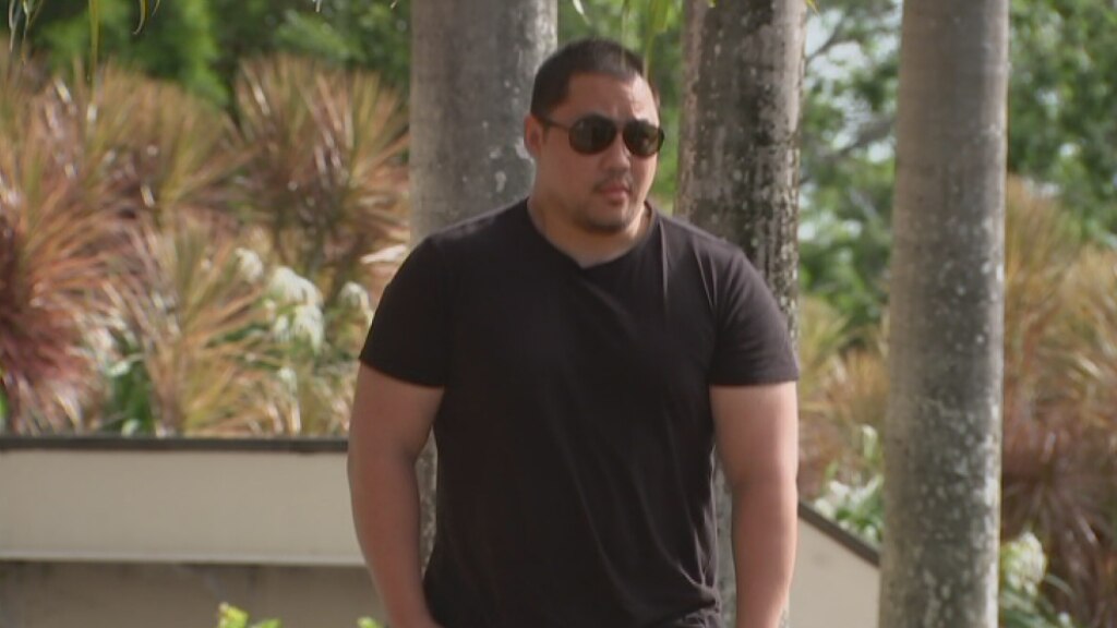 A man in a black t-shirt walking apprehensively towards court.