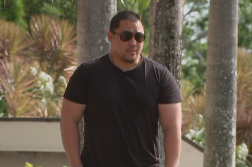 A man in a black t-shirt walking apprehensively towards court.