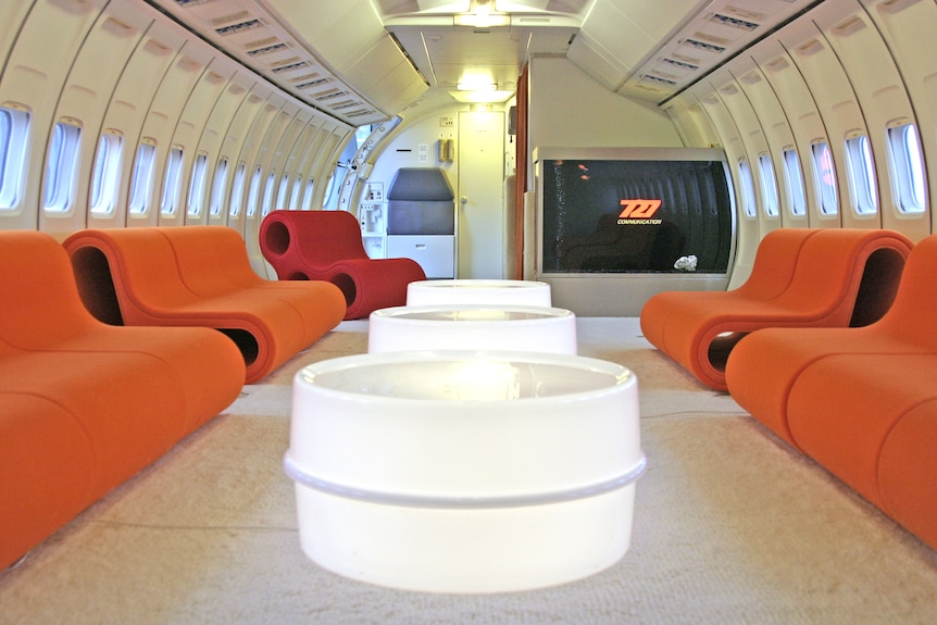 Bright orange chairs inside an airplane converted to a conference centre.