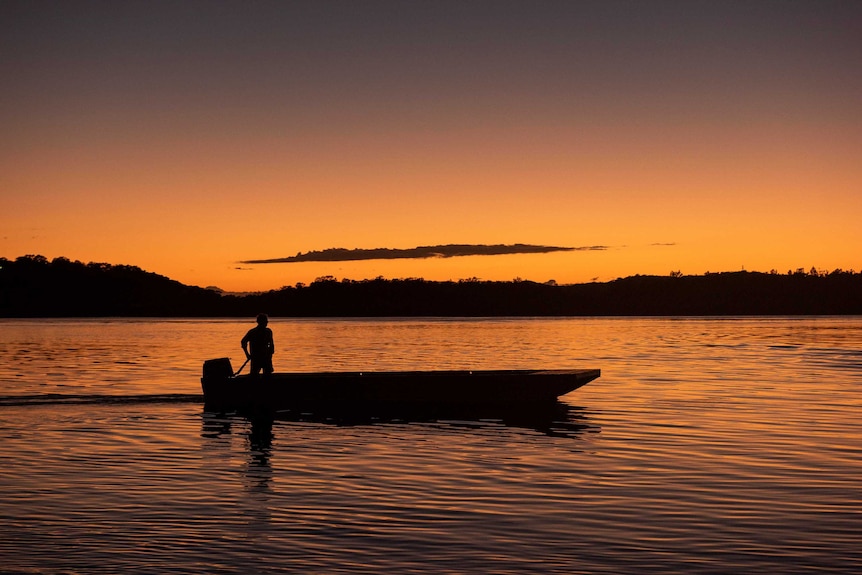 The silhouette of a man in a boat at sunset