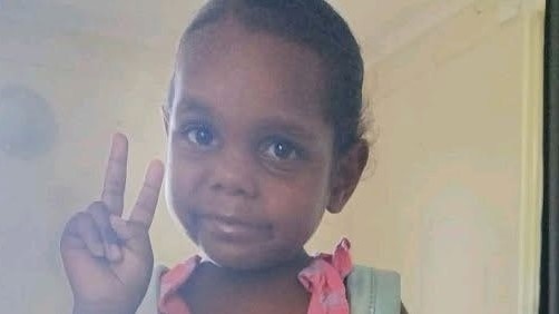 Young girl in pink dress does peace sign with fingers