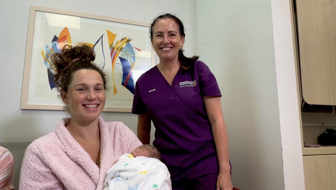 Mum with baby and smiling midwife