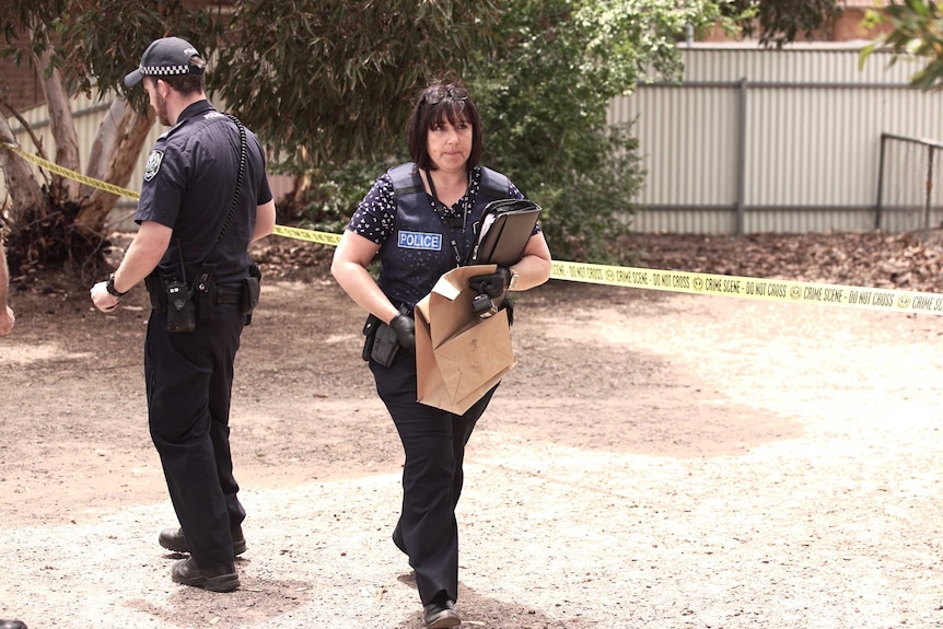 A police officer walks with brow n paper bags