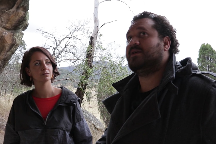 An Aboriginal woman (left) and man (right) view ancient Aboriginal sites.