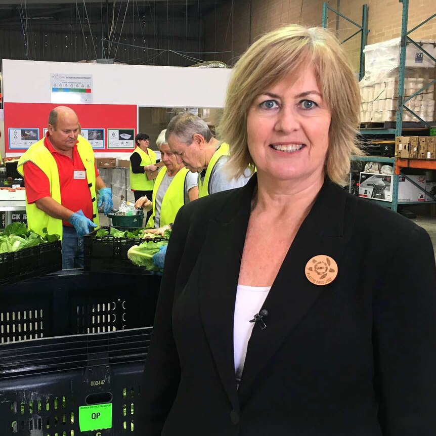 Food Rescue's Julie Broad in foreground, as sorters organise food in baskets behind her.