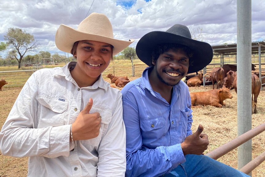 Lettoya Haji-Ali and Kendrick James sitting on the top rail of the cattle yards in front of their freshly yarded cattle.