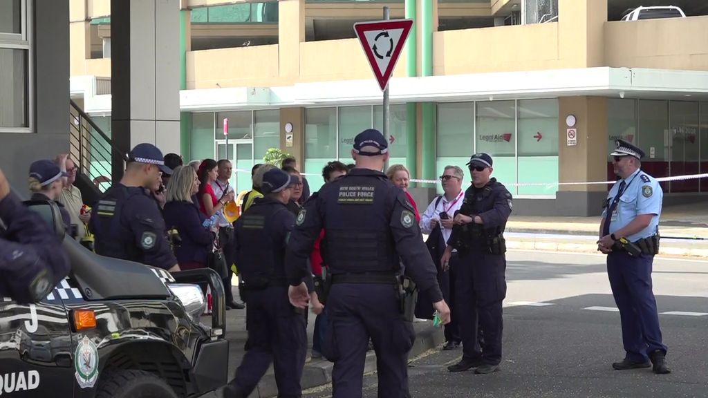 Police officers approach a crowd of people standing around on a street.