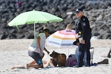A Queensland police officer on the beach with people at Burleigh Heads on the Gold Coast.