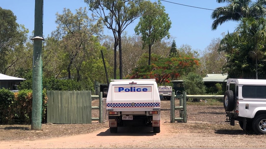 A police car in a driveway and another police car next to a house on a semi-rural property