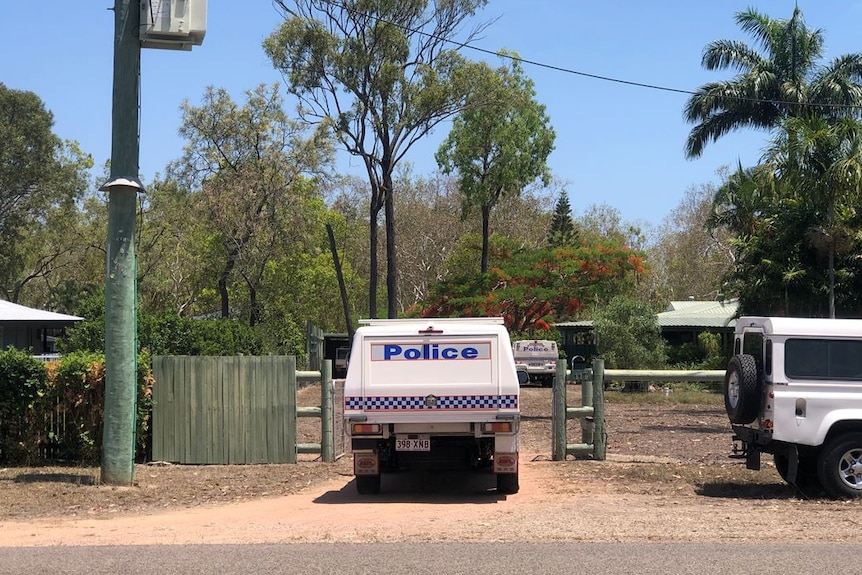 A police car in a driveway and another police car next to a house on a semi-rural property