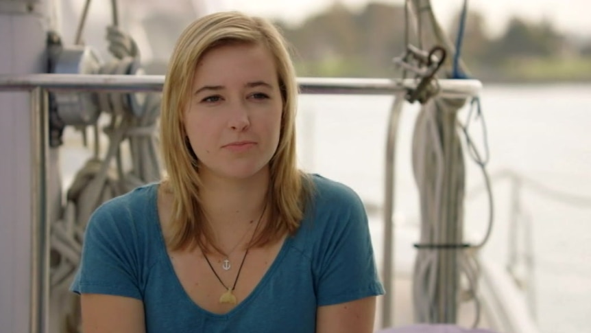 A woman sits on a boat and speaks to the media