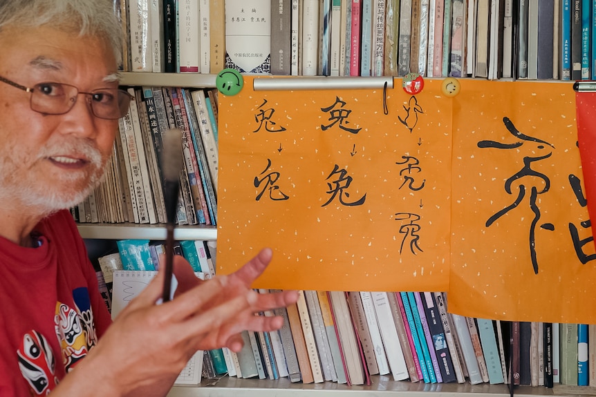 Franz holding a paintbrush next to different versions of the Chinese character for rabbit.