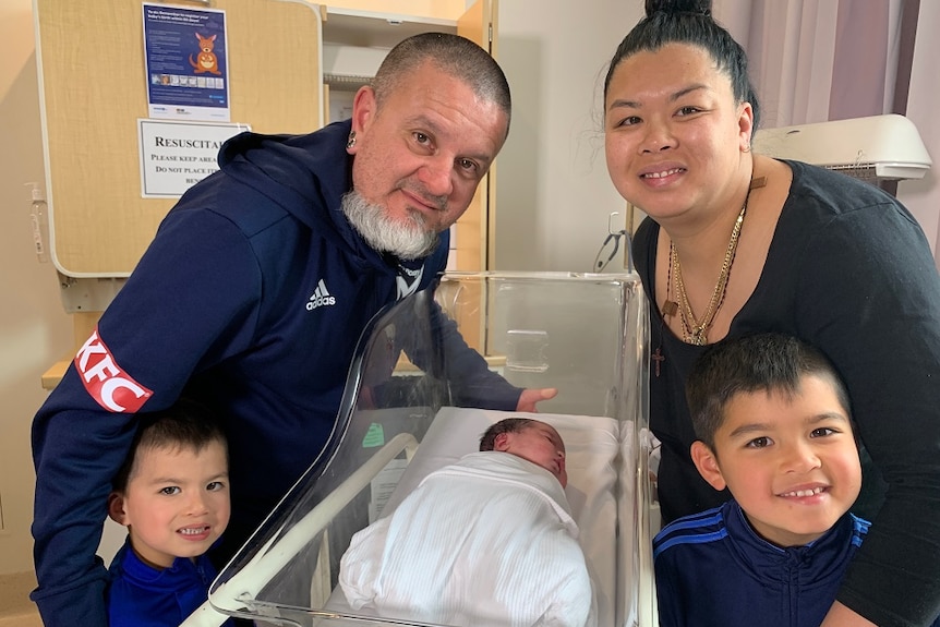 The Martinez family with their two son's Luis 4 and Dominico 6 at the hospital with their newborn baby Mia in a baby bed.