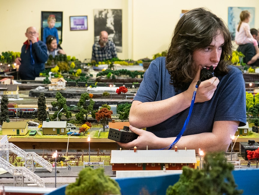 Two men standing inside model railway set using radio communications equipment.