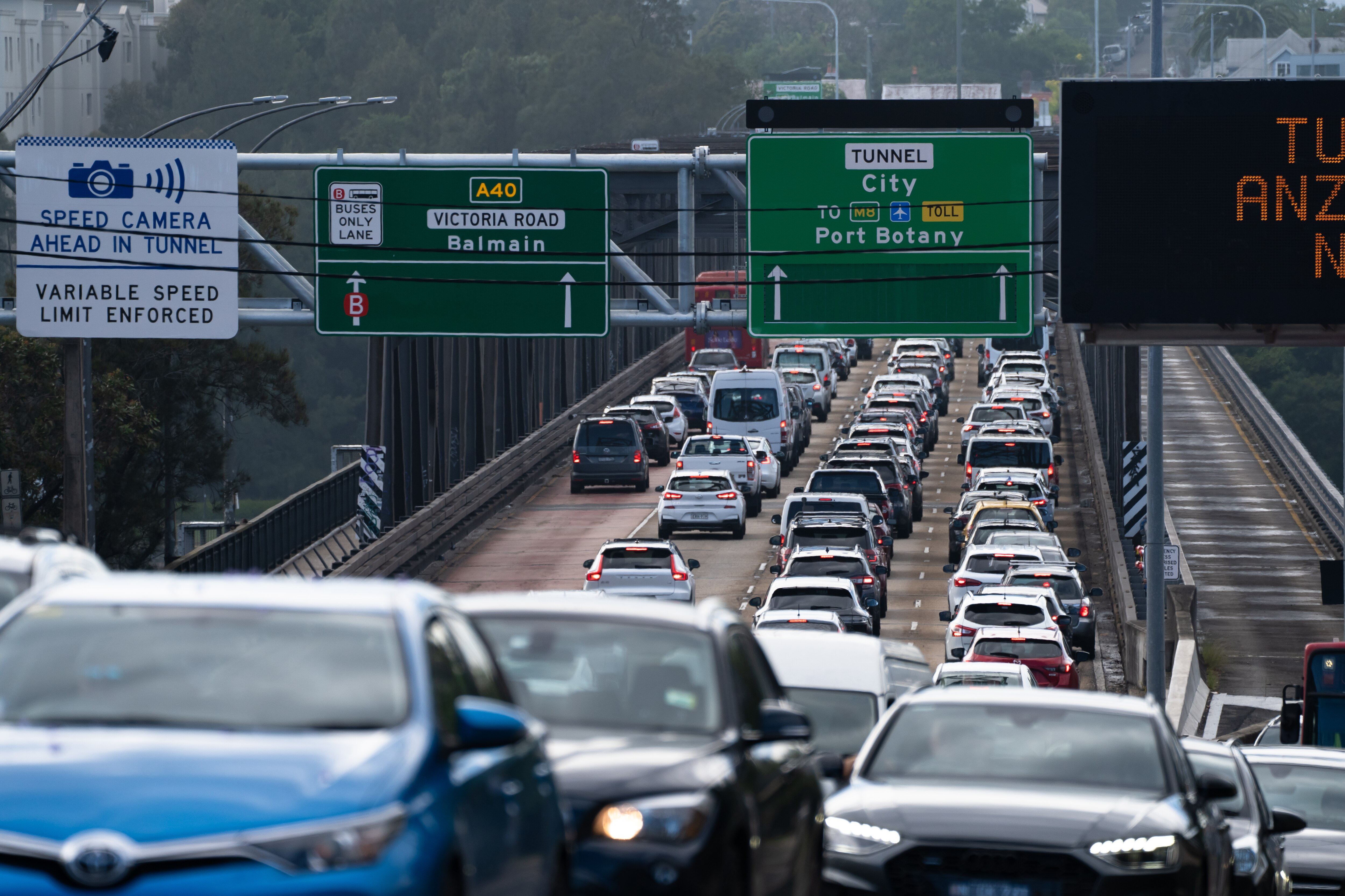 Image shows congestion and traffic delays. You can see cars, grey road on a gloomy day.