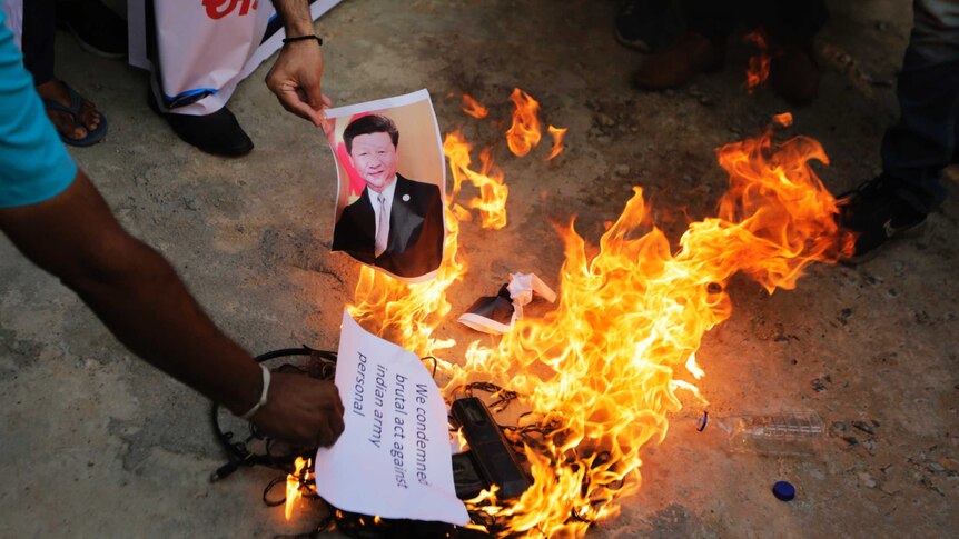 An Indian man burns a photograph of Chinese president Xi Jinping during a protest.