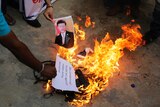 A photograph of the Chinese president is thrown into a fire.