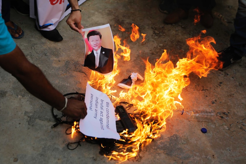 An Indian man burns a photograph of Chinese president Xi Jinping during a protest.