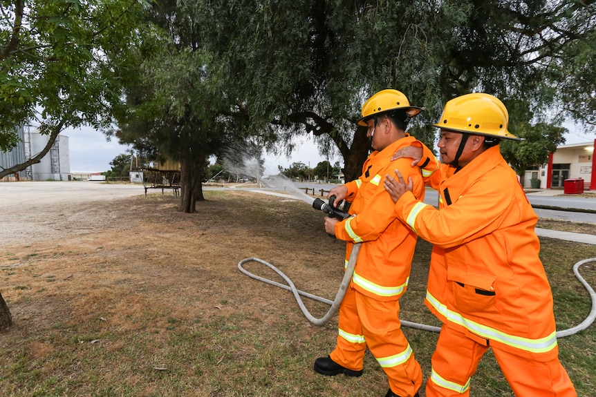 Two Filipino members of the Pyramid Hill CFA practice with  the fire hose.