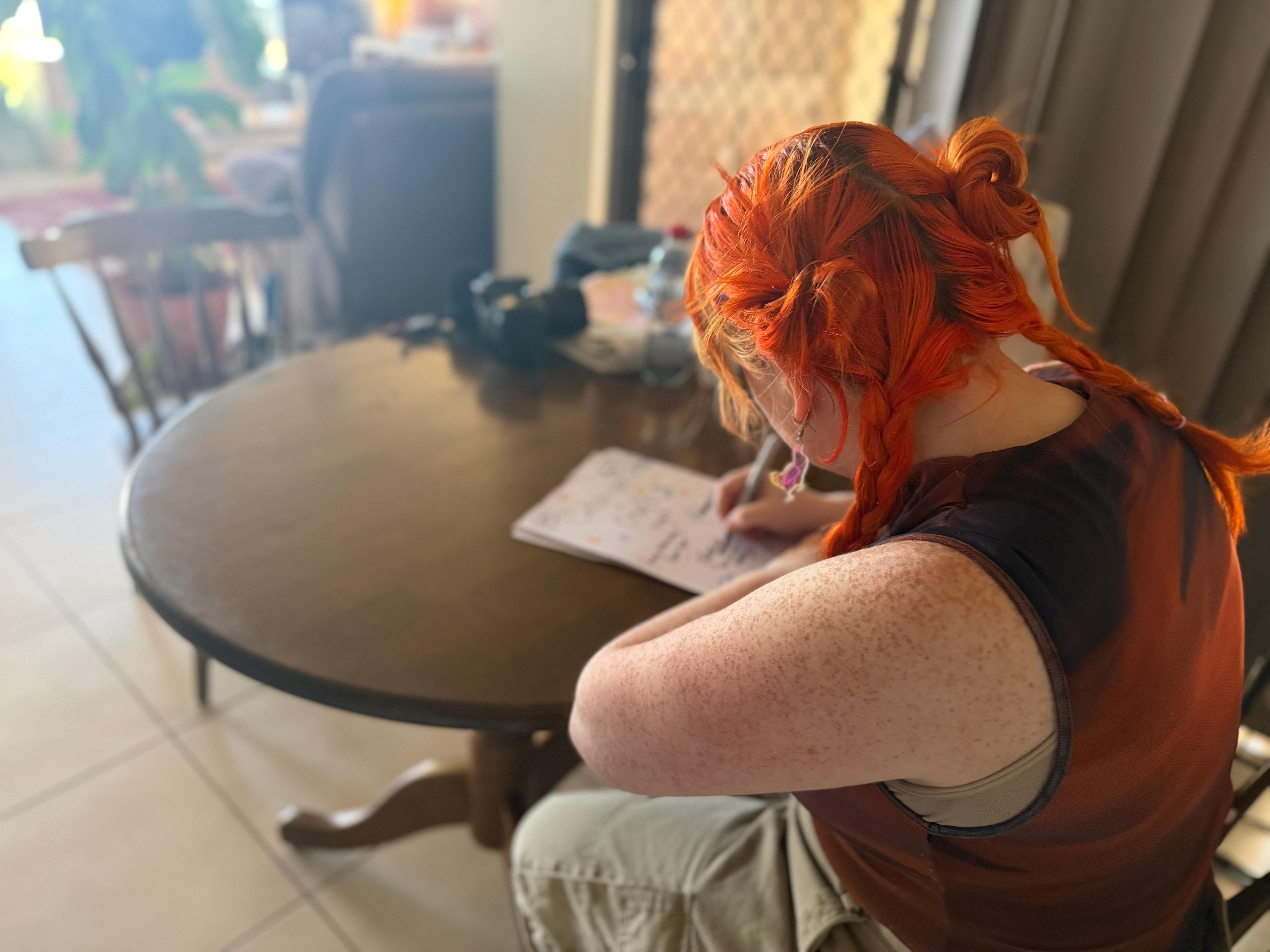 A woman sits at a desk and draws posters